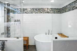 Bathroom with a freestanding bath, a stall shower, and tile walls