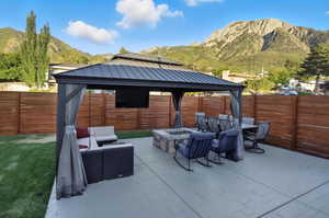 Fenced backyard with a gazebo, a mountain view, an outdoor living space with a fire pit, and a patio area