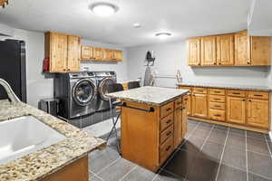 Laundry area with washing machine and clothes dryer, cabinet space, a textured ceiling, and dark tile patterned floors