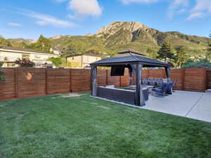 Fenced backyard with outdoor lounge area, a gazebo, a patio area, and a mountain view