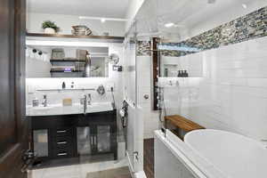 Full bath featuring tile walls, a shower stall, double vanity, a garden tub, and tile patterned flooring