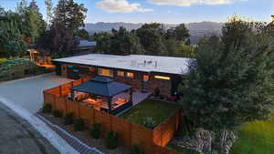Back of house featuring a gazebo, a fenced backyard, a mountain view, and stone siding