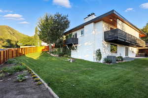 Back of property with a balcony, a chimney, stucco siding, and a mountain view