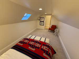 Unfurnished bedroom featuring carpet flooring, a skylight, lofted ceiling, and recessed lighting