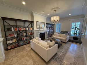 Living area with crown molding, a chandelier, recessed lighting, and a fireplace