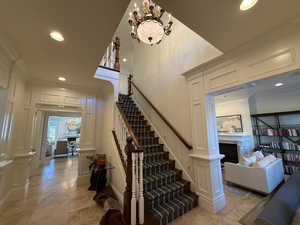 Staircase featuring recessed lighting, a fireplace, ornamental molding, a chandelier, and tile patterned floors