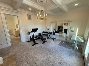 Workout area featuring ornamental molding, coffered ceiling, recessed lighting, and a chandelier