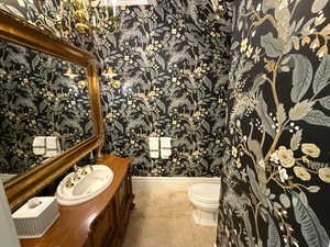 Bathroom with wallpapered walls, vanity, and tile patterned floors