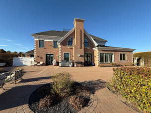 Rear view of property with french doors, brick siding, a chimney, and a patio area