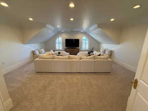 Carpeted living area with crown molding, recessed lighting, and lofted ceiling