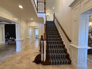 Staircase with a decorative wall, recessed lighting, and crown molding