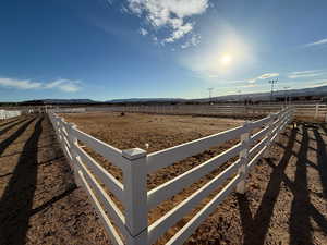 View of yard with a view of countryside, an enclosed horse arena, and a mountain view