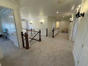 Hall with an upstairs landing, light colored carpet, ornamental molding, and recessed lighting