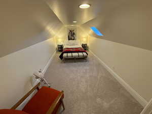 Bedroom featuring lofted ceiling and carpet