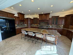Kitchen featuring high end appliances, decorative backsplash, recessed lighting, a kitchen breakfast bar, and stone counters