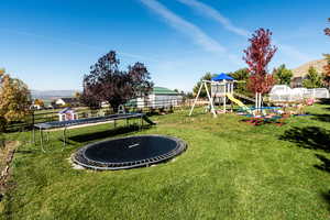 View of yard featuring a trampoline and a playground