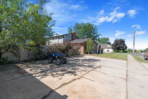 View of home's exterior featuring a chimney, brick siding, and a yard