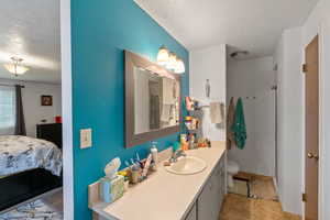 Full bath featuring a textured ceiling, vanity, connected bathroom, and curtained shower