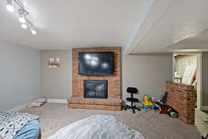 Carpeted bedroom featuring a textured ceiling, a fireplace, and a textured wall
