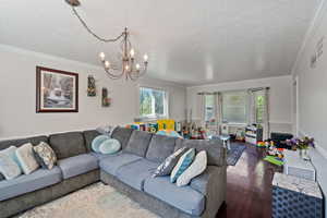 Living area featuring crown molding, hardwood / wood-style flooring, a chandelier, and a textured ceiling