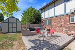 Wooden deck featuring a storage shed and an outdoor fire pit