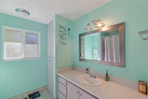 Full bath with vanity, tile patterned flooring, and a textured ceiling