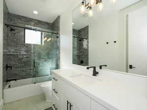 Bathroom with vanity, shower / bath combination with glass door, tile patterned flooring, and recessed lighting