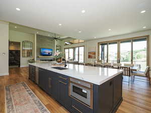 Kitchen featuring light wood-style floors, open floor plan, recessed lighting, a large island with sink, and a ceiling fan