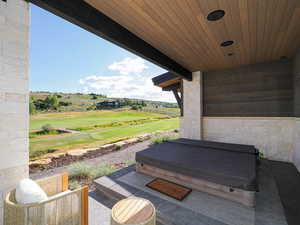 View of patio with a covered hot tub and golf course view