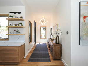 Hallway with a chandelier, light wood finished floors, and recessed lighting