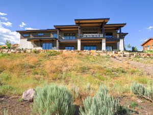 Back of property with a balcony and stone siding