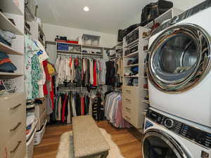 Spacious closet featuring stacked washer and clothes dryer and wood finished floors