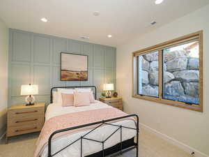 Bedroom with a decorative wall, recessed lighting, and light colored carpet