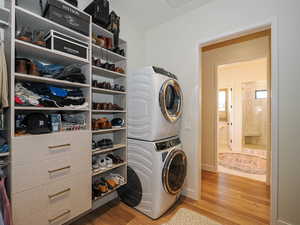 Laundry area featuring stacked washing machine and dryer and wood finished floors