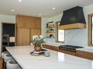 Kitchen featuring open shelves, custom exhaust hood, light countertops, recessed lighting, and appliances with stainless steel finishes