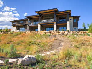 Rear view of property featuring a balcony and stone siding