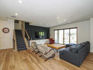 Living area with light wood-style flooring, stairway, and recessed lighting