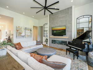 Living room featuring recessed lighting, wood finished floors, a ceiling fan, a fireplace, and a chandelier