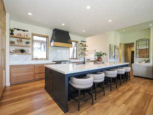 Kitchen with open shelves, custom exhaust hood, a large island, recessed lighting, and a kitchen bar