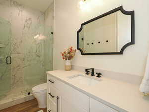 Bathroom featuring vanity, a marble finish shower, and wood finished floors