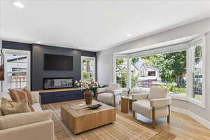 Living area with plenty of natural light, light wood-style flooring, recessed lighting, and a glass covered fireplace