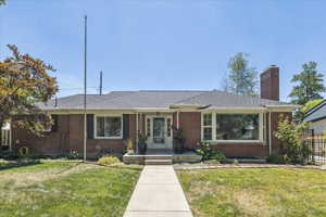 View of front of property with brick siding, a chimney, and roof with shingles