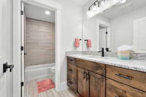 Full bathroom with vanity, wood finished floors,  shower combination, and recessed lighting
