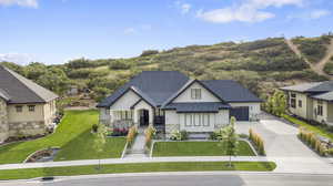View of front of property featuring stone siding, concrete driveway, board and batten siding, and a shingled roof