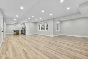 Unfurnished living room with recessed lighting, light wood-type flooring, and bar