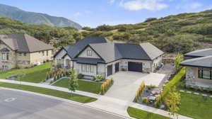 View of front facade with stone siding, concrete driveway, a garage, a shingled roof, and a front yard