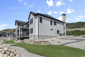 Rear view of property with a mountain view, a balcony, a chimney, and a yard