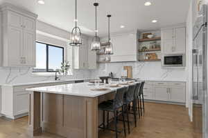 Kitchen featuring open shelves, light wood finished floors, high end fridge, a breakfast bar, and a kitchen island