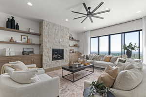 Living room with ceiling fan, wood finished floors, recessed lighting, and a stone fireplace
