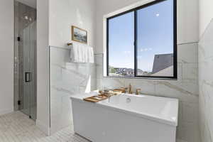 Full bathroom featuring a freestanding bath, a shower stall, and tile walls